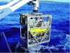 Figure 6 - The H2000 intervention ROV from Exail (formerly ECA robotics) and its garage/TMS (Tether Management System). The two white arms actuated by cylinders form the mobile part of the LARS (Launch And Recovery System). This 900 kg robot can operate at depths of up to 2,000 m (copyright: Exail – ECA).