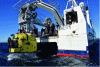 Figure 9 - Ifremer's HROV Ariane during its recovery by the vessel l'Europe. Two external and two through thrusters can be seen on the side of the vehicle. The left-hand side of the image shows the front of the vehicle. One of the cameras (top), the sample drawer (bottom) and one of the folded manipulator arms can be seen. Raised by a winch attached to the gantry, Ariane is housed in a docking system (in gray below the gantry) which stabilizes the robot as it moves in and out of the gantry (credit: Ifremer, Olivier Dugornay).
